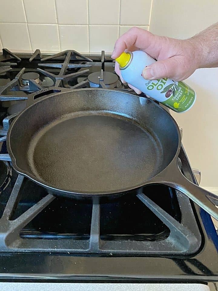 spraying oil in a cast iron skillet